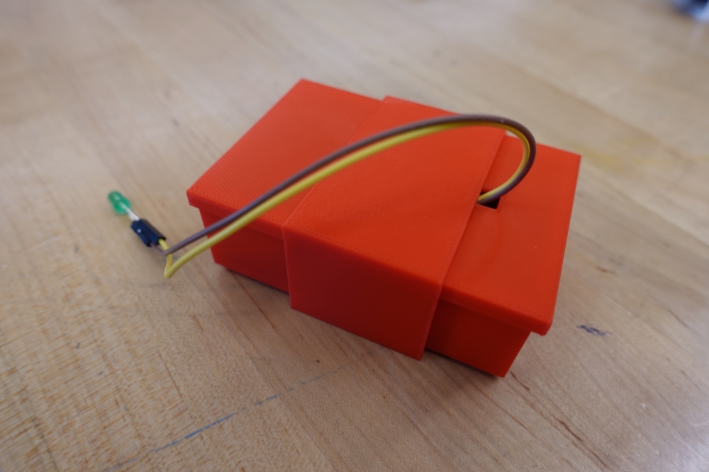 Red 3D printed enclosure with a green LED sticking out.