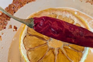 Close up of drink with salted rim, lemon, and red chili pepper