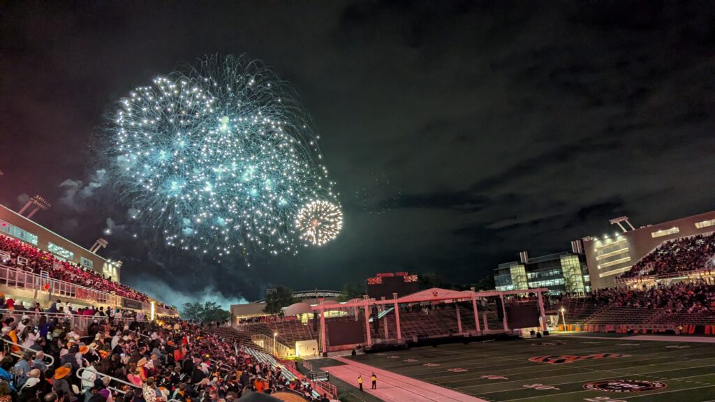 Fireworks bursting in front of a full stadium crowd.