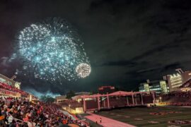 Fireworks bursting in front of a full stadium crowd.