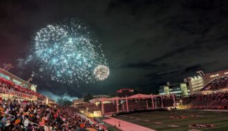 Fireworks bursting in front of a full stadium crowd.